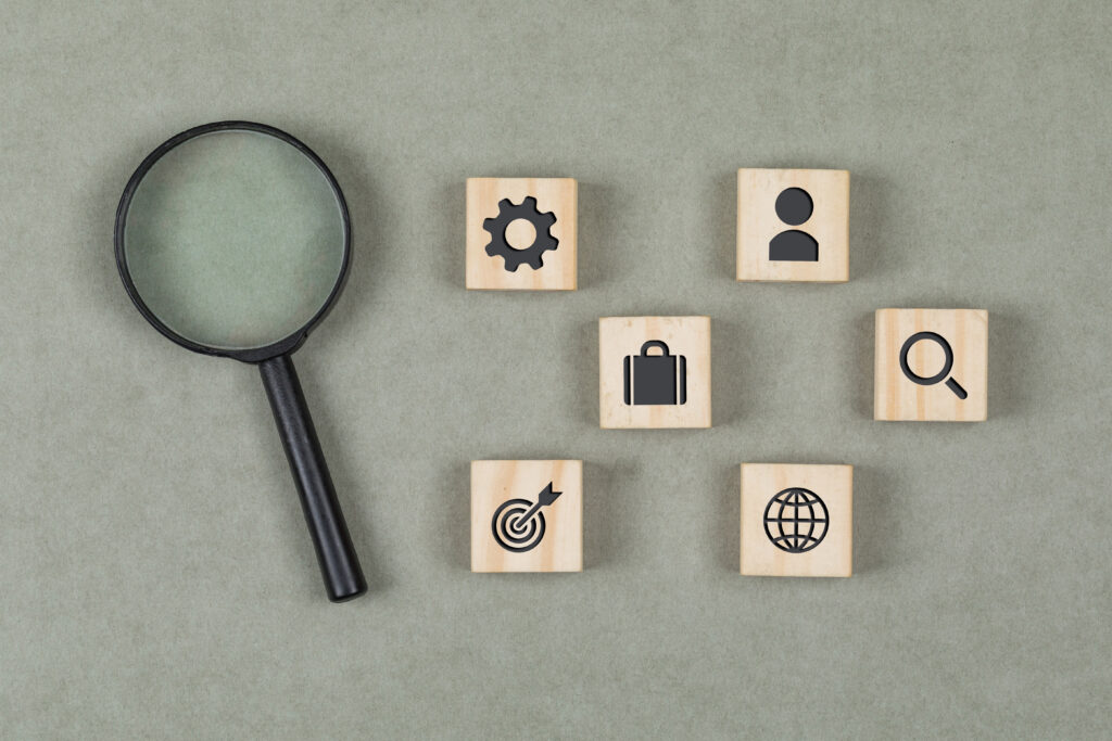 Financial Concept With Wooden Cubes, Magnifying Glass On Grey Background Flat Lay.